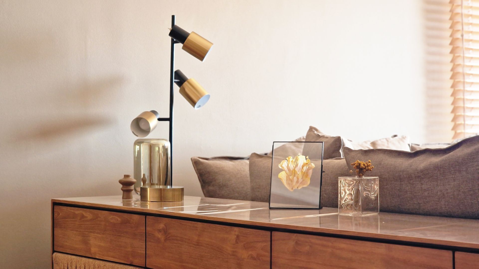 A wooden console table with a modern lamp, decorative items, and a framed picture.