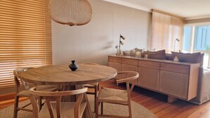 A modern dining area with a round wooden table, two chairs, and a woven pendant light. - Casa Ulli by LovelyStay (Canico)