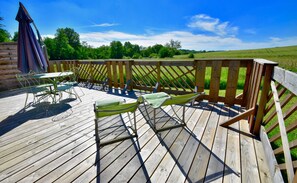 A wooden deck with outdoor furniture, including a table and chairs, overlooking a green landscape. - Chalet, Nature, Spa & Sauna 2* #2 (La Réunion)