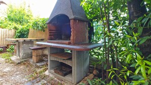A stone-built outdoor pizza oven with a flat stone countertop, surrounded by greenery and a wooden fence. - Apartment 1347/12668 (Istria - Pula), 1500m from the beach (Pula)
