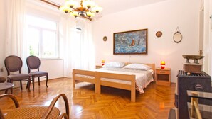 A room with a wooden bed, two chairs, a table, a painting, a mirror, and a stove. - Apartment 1347/12668 (Istria - Pula), 1500m from the beach (Pula)