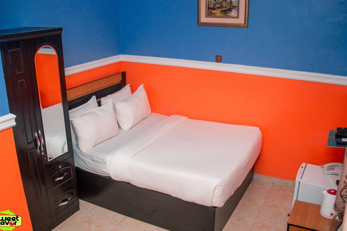 Une chambre à coucher comprenant un lit, une armoire et une table de chevet avec un téléphone et une lampe.