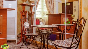 A dining area with a round table and chairs, a vintage air conditioner, and a decorative vase with flowers. - Sweet Savor Hotels and Suites Annex (Lagos)