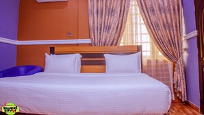 A bedroom with a bed, an air conditioner, and curtains. - Sweet Savor Hotels and Suites Annex (Lagos)