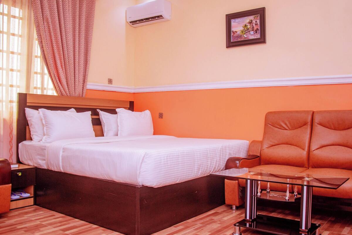 Une chambre d’hôtel équipée d’un lit, d’une chaise, d’une petite table et d’un appareil de climatisation.