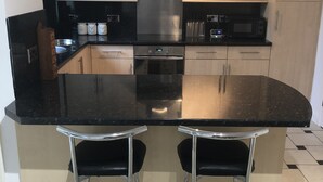 A modern kitchen with a central island, stainless steel appliances, and a bar area. - Remarkable 3-bed House in Ipswich With a Zen Vibe (Ipswich)