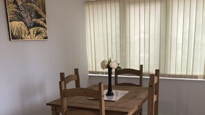 A dining area with a wooden table and chairs, a vase with flowers, and a painting on the wall. - Remarkable 3-bed House in Ipswich With a Zen Vibe (Ipswich)