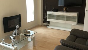 A modern living room with a grey sofa, a white cabinet, and a black chair. - Remarkable 3-bed House in Ipswich With a Zen Vibe (Ipswich)