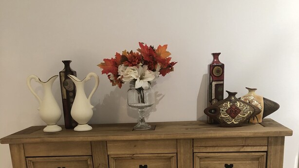 A wooden cabinet with multiple drawers and a vase with flowers on top. - Remarkable 3-bed House in Ipswich With a Zen Vibe (Ipswich)