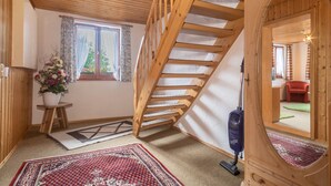 Eine Holztreppe, ein Blumentopf und ein roter Sessel in einem Raum mit Holzboden und -wänden.