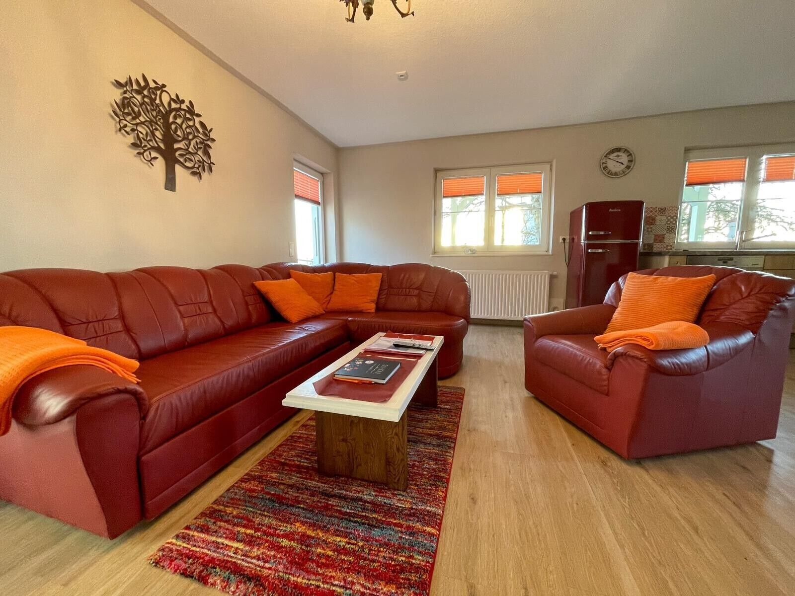 A living room with a large red sofa, a smaller red armchair, a coffee table, and a patterned rug.