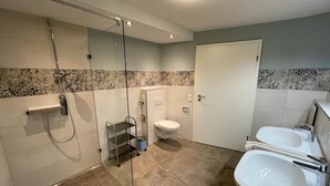 Ein Badezimmer mit Duschkabine, Toilette und zwei Waschbecken.