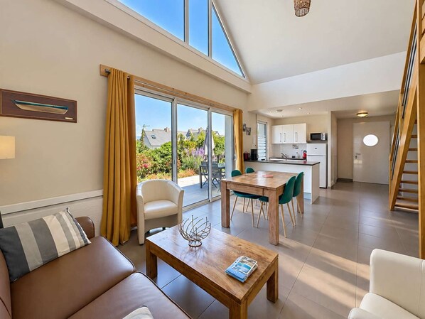 A modern apartment with a dining area, kitchen, and a large sliding glass door leading to a balcony.