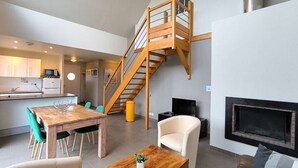 Ein modernes Interieur mit Essbereich, einer Couch, einem Fernseher und einer Treppe.