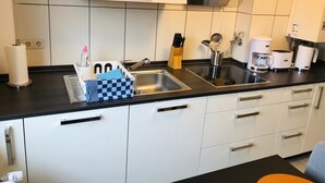 Une cuisine moderne dotée d’un évier en acier inoxydable, de meubles blancs et d’un plan de travail noir.