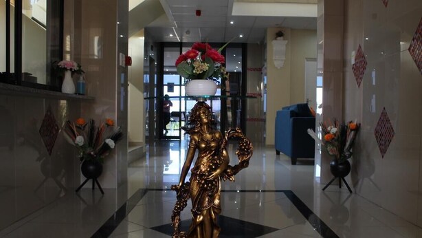 Un hall d’entrée orné d’une statue dorée, doté d’un comptoir de réception et agrémenté de compositions florales.