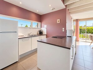 Een moderne keuken met witte kasten, een groot eiland en uitzicht op de omgeving.