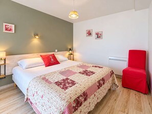 Ein Schlafzimmer mit einem Bett, einem roten Sessel und zwei Wandleuchten.