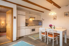 A kitchen with white cabinets, a stove, and a dining table with chairs.