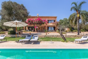A two-story house with a swimming pool, outdoor seating, and a garden.