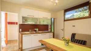 Una cocina compacta con armarios blancos, una encimera de madera y un ventanal sobre el lavabo.