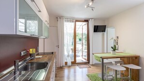 Una cocina moderna con un lavamanos, una zona de comedor con mesa y sillas, y un televisor montado en la pared.
