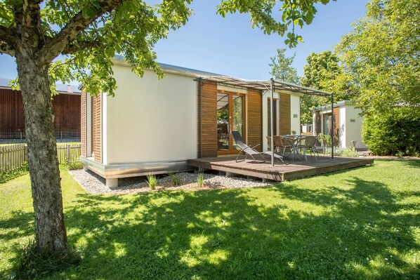 Une maison moderne avec un patio, un arbre et une pelouse.
