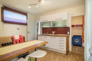 Une cuisine compacte comprenant une table à manger, une chaise haute pour enfant et un parc pour bébé.