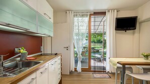 A modern kitchen with a wooden countertop, stainless steel sink, and a dining area with a table and chairs.