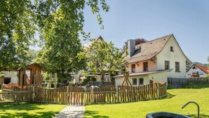 A courtyard with a stone well, a wooden fence, and a building with a tiled roof.