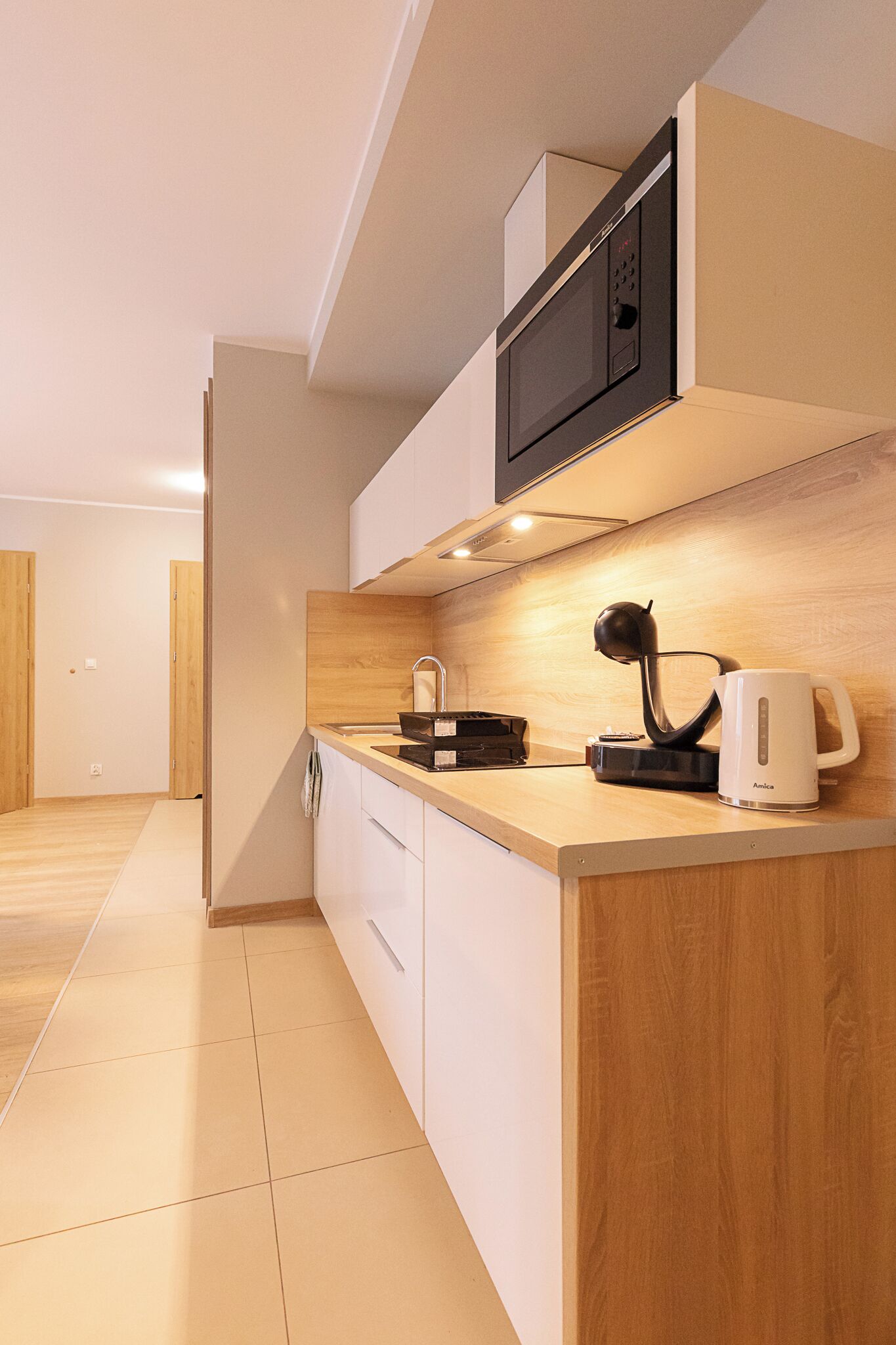 A modern kitchen with a microwave, kettle, and coffee maker on the counter.