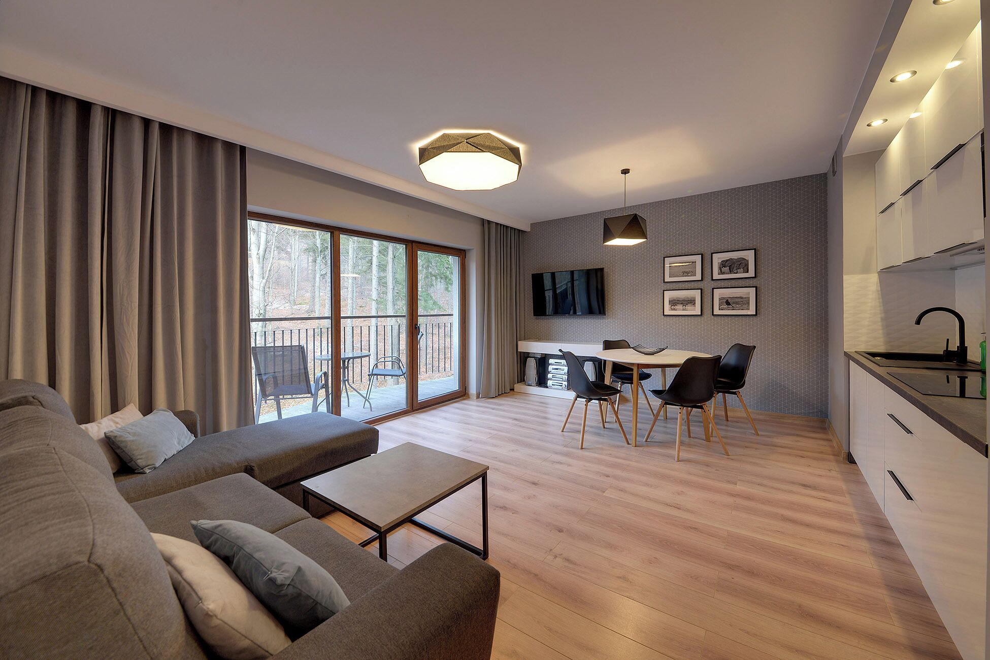 A modern living room with a sofa, a dining area with a table and chairs, a kitchen with a sink, and a large window with curtains.