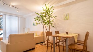 Un coin repas comprenant une table, des chaises, une plante, un canapé et un radiateur.