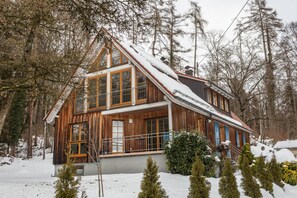 Une cabane en bois dotée d’un balcon, entourée d’arbres et de neige.