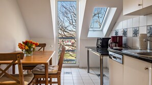 A kitchen with a dining table, chairs, a coffee machine, and a view of a tree through a window.