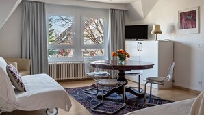 A modern room with a dining table, two chairs, a sofa, a TV, and a radiator.