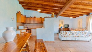 Una cucina rustica con mobili in legno, un tavolo da pranzo e un divano in zona soggiorno.