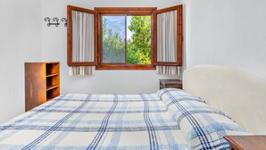 Una camera da letto con un letto grande, una testiera in legno, una finestra con tende, un comodino e una mensola in legno.