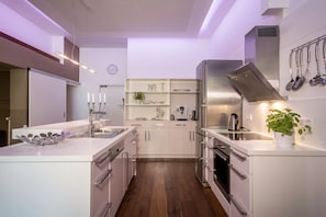 Une cuisine moderne avec des meubles blancs, des appareils en acier inoxydable et un îlot central.