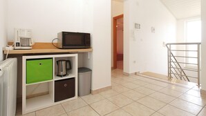 Une petite cuisine équipée d’un four à micro-ondes, d’une machine à café et de placards de rangement.