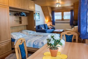 Una habitación acogedora con una cama, una mesa de comedor con una planta en maceta y un sofá azul.