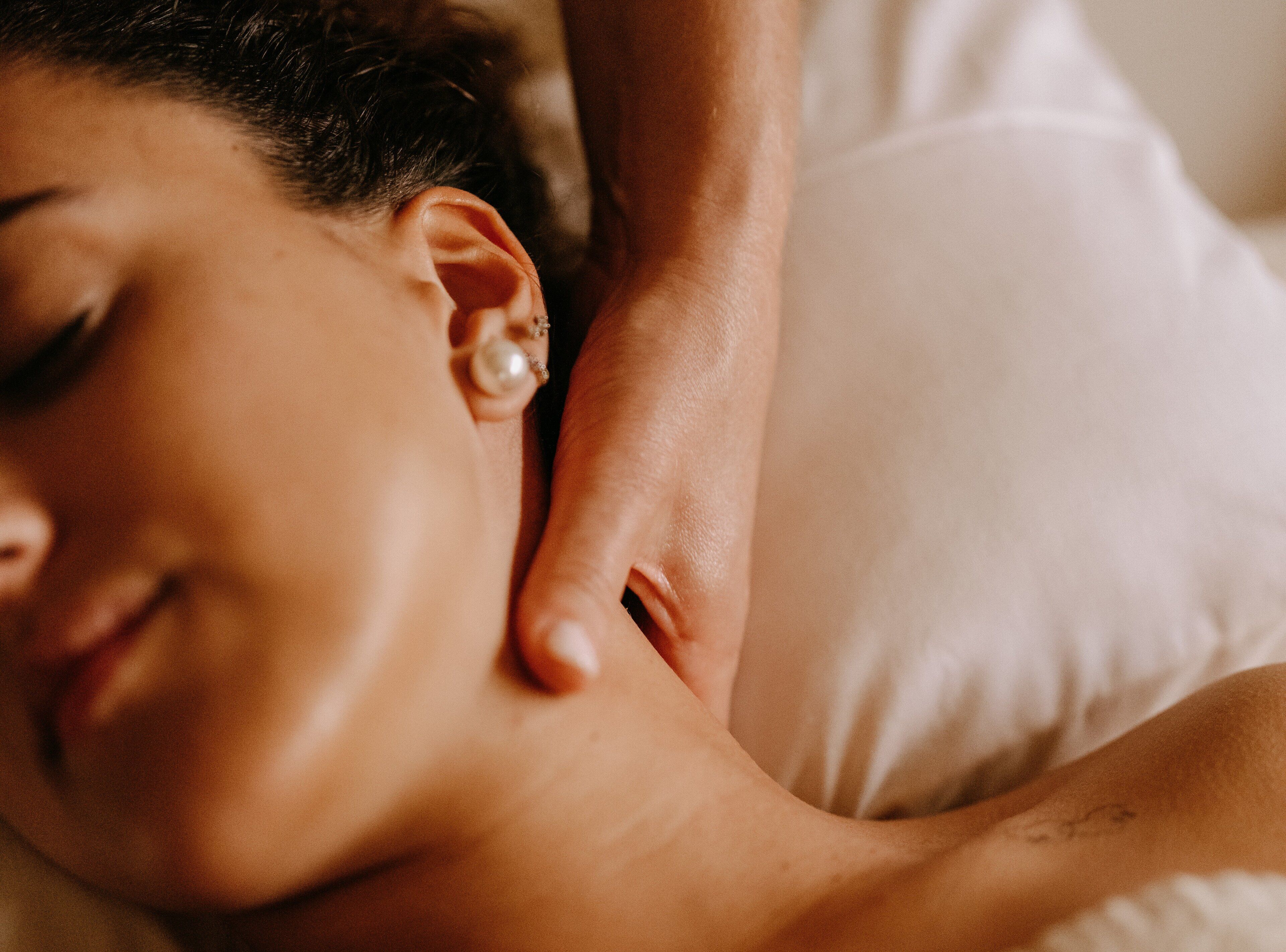 A close-up of a person lying down with a hand gently touching their shoulder.