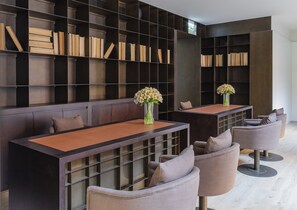 A modern library with bookshelves, two tables with vases, and comfortable seating. - Casa da Companhia Hotel & Spa, Vignette Collection by IHG (Porto)