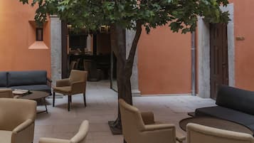 Un espacio interior acogedor con sofás y sillones, un árbol grande y una pared de piedra.