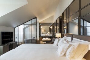 A modern hotel room with a large bed, a TV, a bathroom, and a view through floor-to-ceiling windows. - Casa da Companhia Hotel & Spa, Vignette Collection by IHG (Porto)