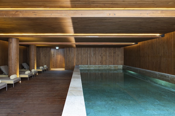 A spa area with wooden walls, a pool, and several lounge chairs.
