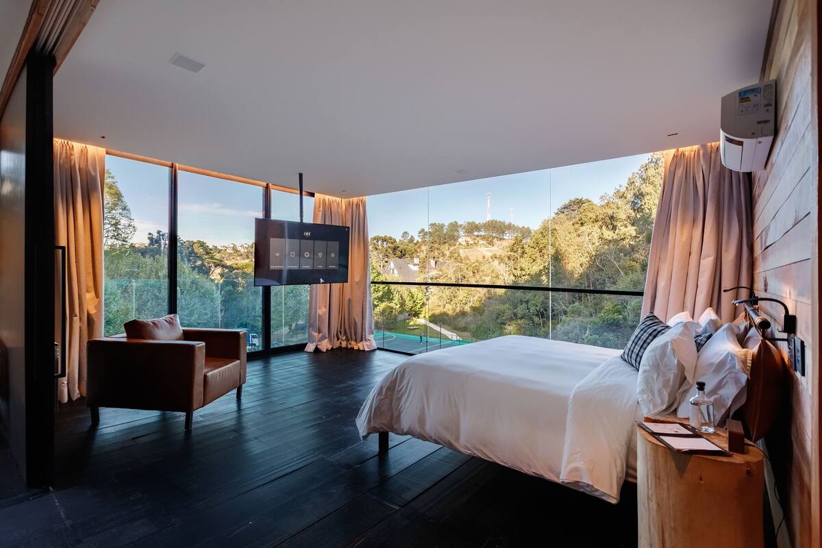 Une chambre moderne dotée d’un grand lit, d’une télévision et d’un balcon offrant une vue panoramique.
