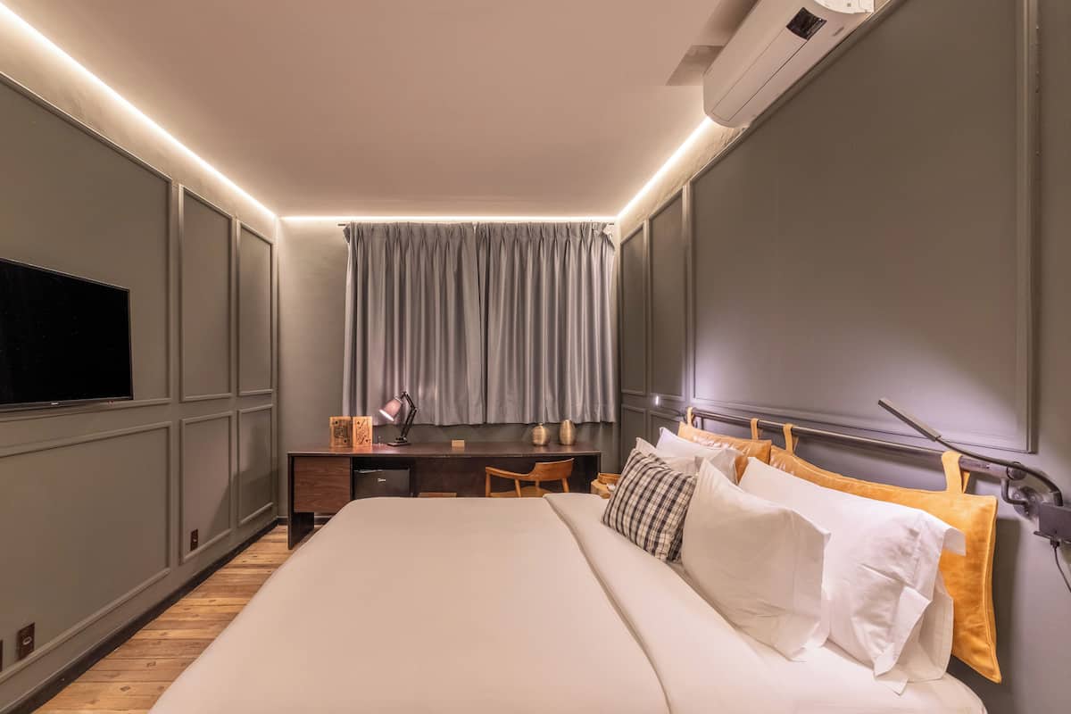 Une chambre d’hôtel moderne, dotée d’un grand lit, d’un bureau et d’une télévision.