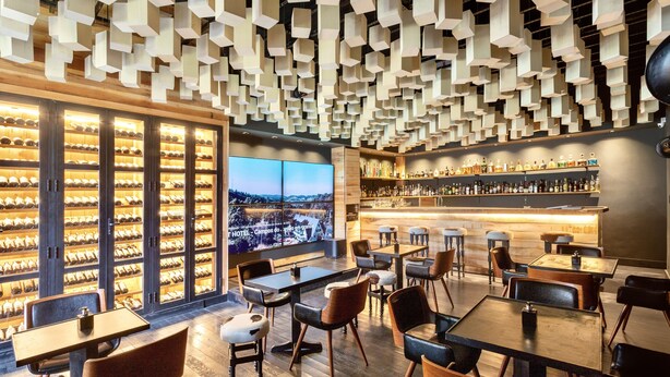 Bar de hotel con bodega de vinos, zona de estar y vistas a la ciudad.