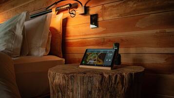 A wooden wall with a mounted device displaying a restaurant menu, a wooden stool, and a sofa with pillows.